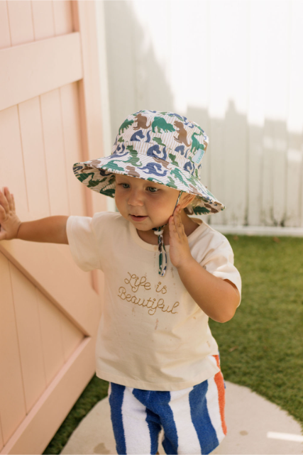 Child leaning on door wearing a dino hat
