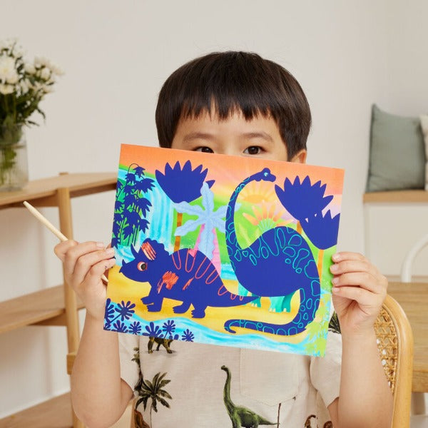 Child holding up one of the TIGER TRIBE Scratch Art - Dinosaur pictures