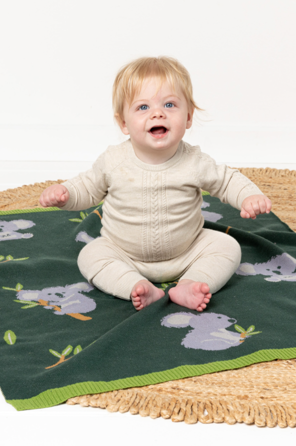 Baby sitting on INDUS DESIGN Kiki Koala Baby Blanket
