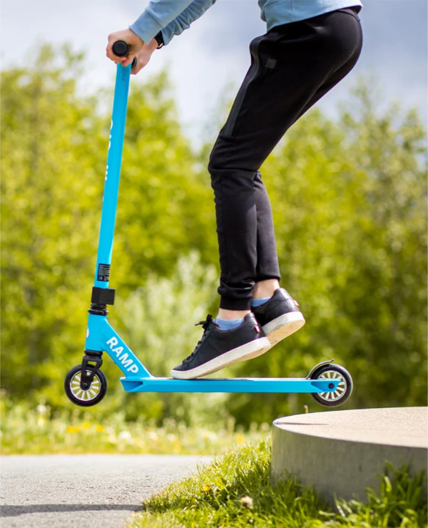 Person riding a blue scooter with 'Ramp' branding outdoors.