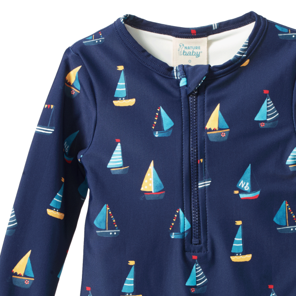 Navy blue baby swimsuit with sailboat pattern on a white background