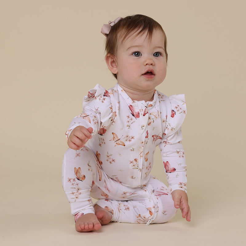 Baby sitting on floor wearing SNUGGLE HUNNY Butterfly Organic Snugglesuit Convertible Romper with Frill