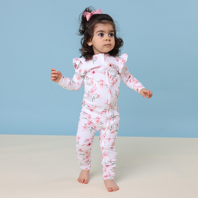 Child wearing a floral onesie against a blue background