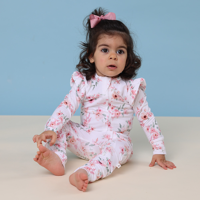 Child wearing a floral onesie against a blue background