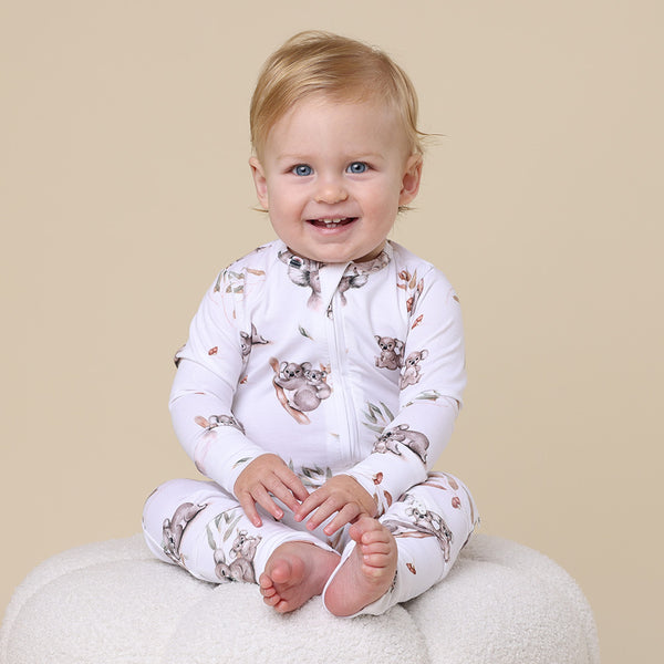 Baby sitting on stool wearing SNUGGLE HUNNY Koala Organic Snugglesuit Convertible Romper