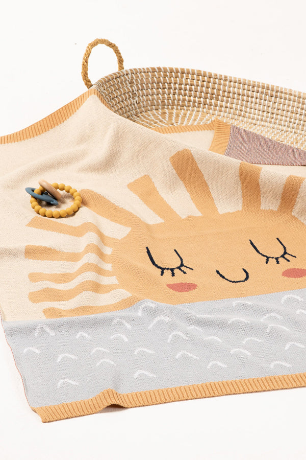 INDUS DESIGN Sunshine Baby Blanket draped over a bassinet