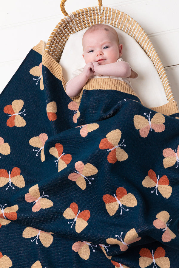 Baby in a bassinet covered in the INDUS DESIGN Beau Butterfly Baby Blanket